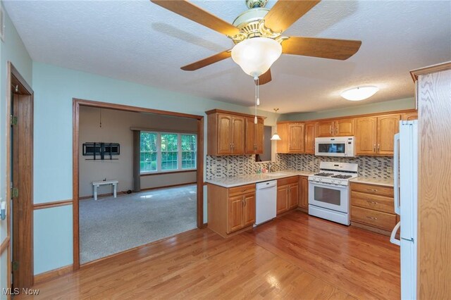 373 Chesapeake Cv, Painesville, OH 44077 - kitchen featuring white appliances, light countertops, light wood finished floors, a ceiling fan, and tasteful backsplash