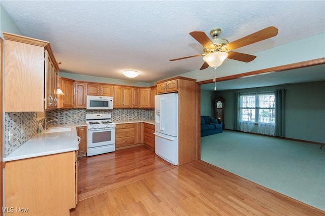 373 Chesapeake Cv, Painesville, OH 44077 - kitchen featuring white appliances, light wood-type flooring, a ceiling fan, light countertops, and backsplash