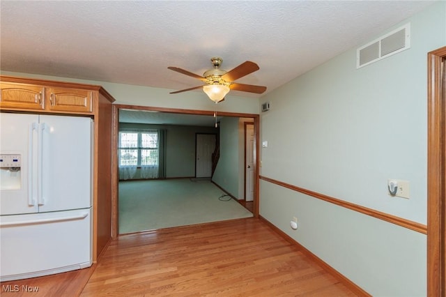 373 Chesapeake Cv, Painesville, OH 44077 - kitchen featuring white fridge with ice dispenser, ceiling fan, light wood-type flooring, brown cabinets, and a textured ceiling