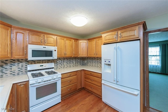 373 Chesapeake Cv, Painesville, OH 44077 - kitchen with white appliances, backsplash, light countertops, light wood finished floors, and a textured ceiling