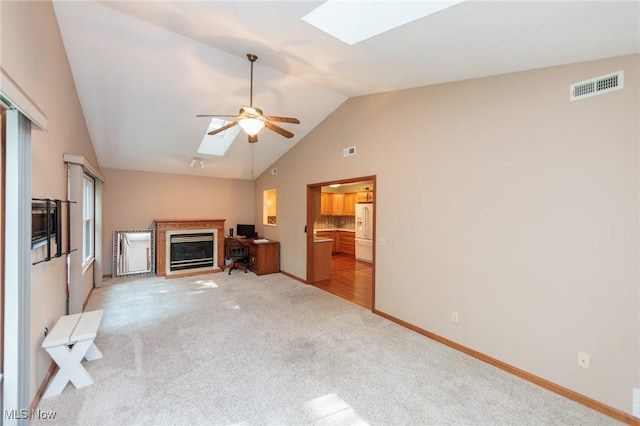 373 Chesapeake Cv, Painesville, OH 44077 - unfurnished living room with a skylight, a ceiling fan, a glass covered fireplace, light carpet, and high vaulted ceiling