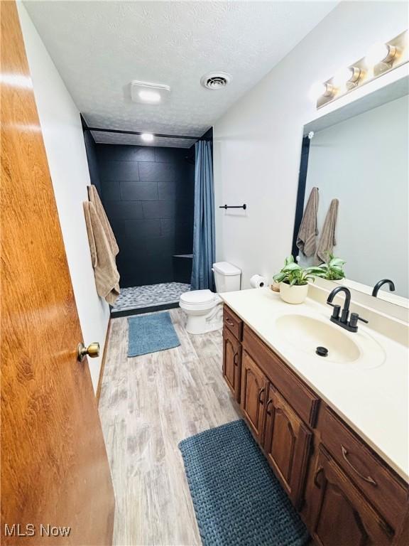 206 E 4th St, Williamstown, WV 26187 - full bath with vanity, a stall shower, wood finished floors, and a textured ceiling