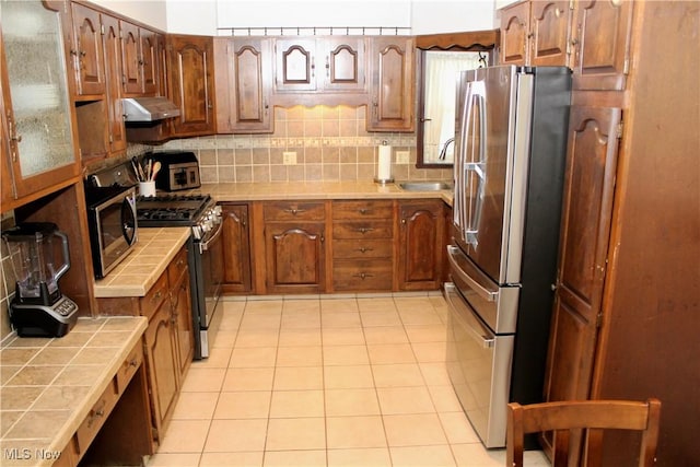 195 W 10th St, Salem, OH 44460 - kitchen featuring stainless steel appliances, tile countertops, under cabinet range hood, and tasteful backsplash