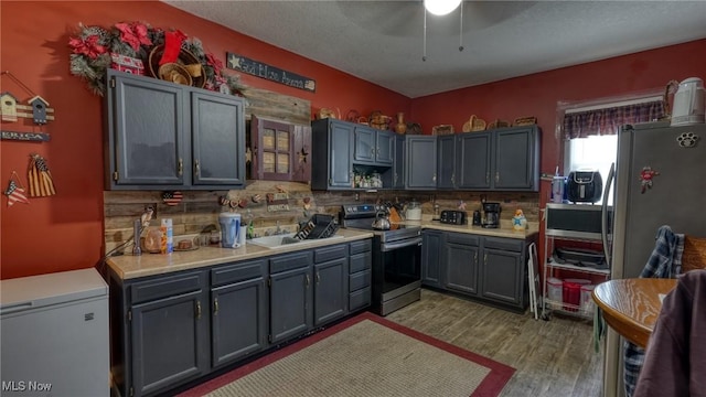 217 Mclaughlin Ave, Byesville, OH 43723 - kitchen with stainless steel appliances, backsplash, wood finished floors, light countertops, and a textured ceiling