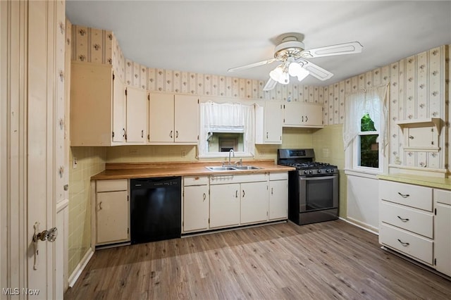 158 Elm St, Leetonia, OH 44431 - kitchen featuring black dishwasher, stainless steel range with gas cooktop, wallpapered walls, ceiling fan, and light wood-style floors