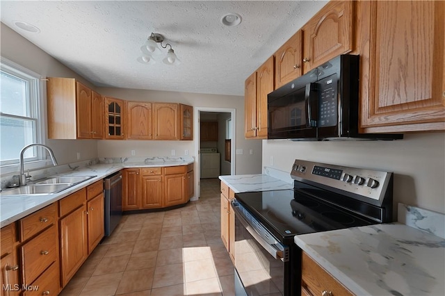 233 Robbies Run, Cortland, OH 44410 - kitchen with stainless steel appliances, glass insert cabinets, washer / dryer, a textured ceiling, and brown cabinetry