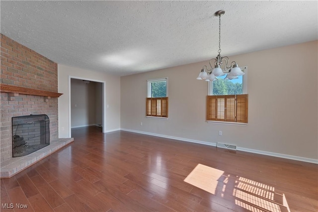 233 Robbies Run, Cortland, OH 44410 - unfurnished living room featuring a textured ceiling, a chandelier, wood finished floors, and a brick fireplace