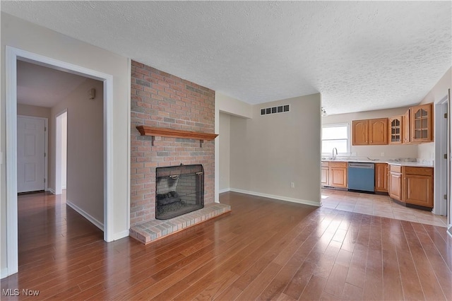 233 Robbies Run, Cortland, OH 44410 - unfurnished living room featuring a textured ceiling, wood finished floors, and a brick fireplace