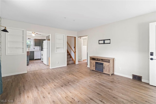 302 Bender Ave, Akron, OH 44312 - unfurnished living room with stairs, light wood finished floors, and ceiling fan
