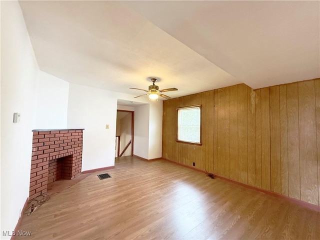 5048 Grove Ave, Lorain, OH 44055 - unfurnished living room featuring light wood-style floors, wood walls, ceiling fan, and a brick fireplace