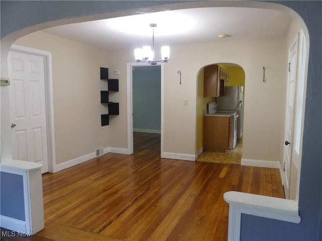 6069 Hyde St, Mentor, OH 44060 - unfurnished dining area with hardwood / wood-style floors, a chandelier, and arched walkways