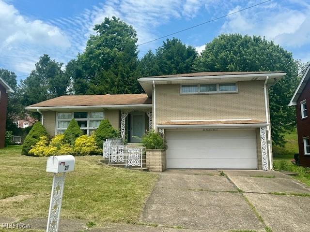 211 Donnell St, Weirton, WV 26062 - split level home with an attached garage, brick siding, concrete driveway, and a front lawn