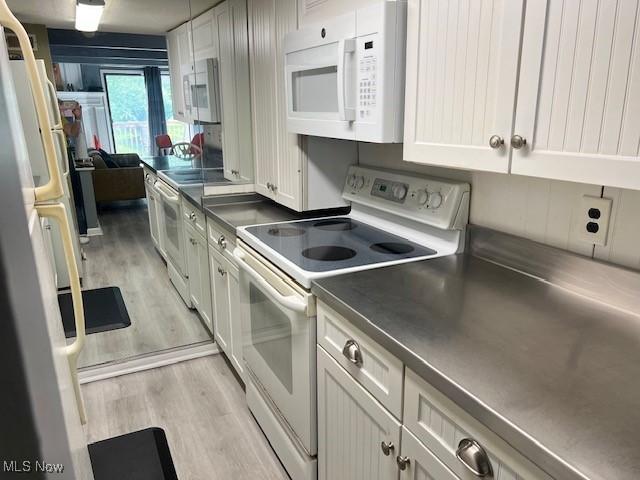 2157 Penguin Ave, Akron, OH 44319 - kitchen featuring white appliances, light wood finished floors, dark countertops, and white cabinets