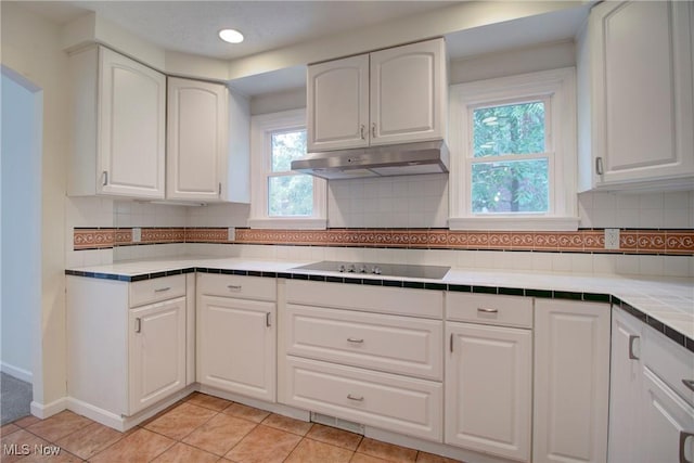 181 Seminary St, Berea, OH 44017 - kitchen with tile counters, under cabinet range hood, white cabinetry, light tile patterned floors, and recessed lighting