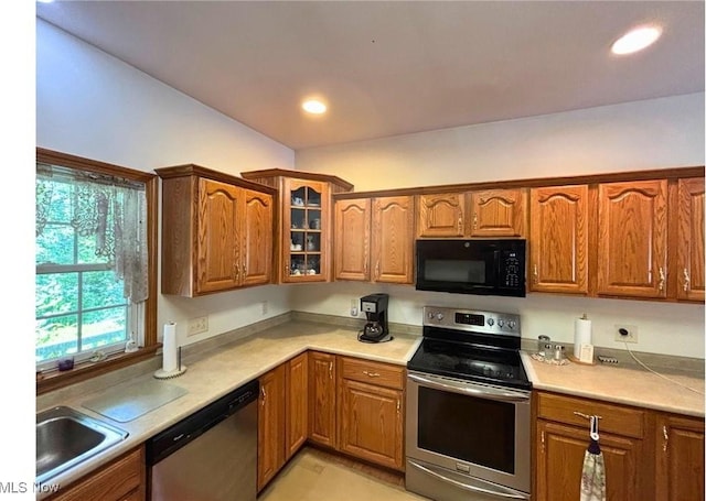 611 Wainwright Rd SE, New Philadelphia, OH 44663 - kitchen with stainless steel appliances, brown cabinetry, glass insert cabinets, light countertops, and recessed lighting
