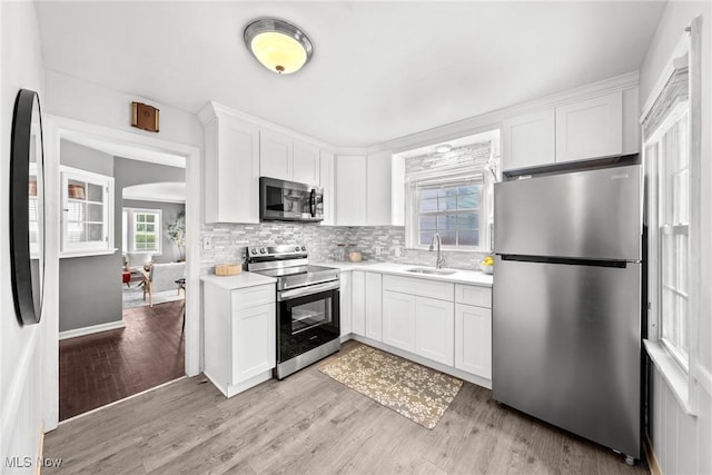 2324 Scholl Rd, University Heights, OH 44118 - kitchen with stainless steel appliances, light wood-style floors, white cabinetry, light countertops, and decorative backsplash
