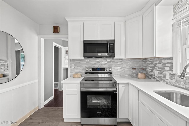 2324 Scholl Rd, University Heights, OH 44118 - kitchen with appliances with stainless steel finishes, white cabinets, light countertops, decorative backsplash, and wood finished floors