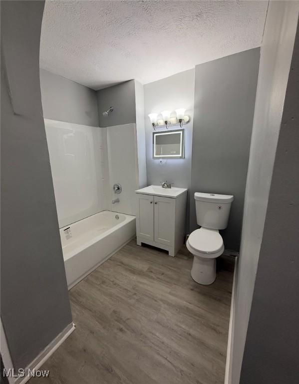 1063 Raymond St, Akron, OH 44307 - bathroom with a textured ceiling, wood finished floors, vanity, and  shower combination