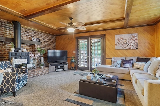 2970 Meadow Ln, Youngstown, OH 44511 - carpeted living room featuring a wood ceiling with exposed beams, a wood stove, wood walls, and a ceiling fan