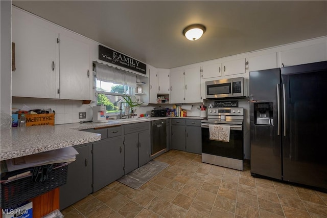 1819 49th St NW, Canton, OH 44709 - kitchen featuring appliances with stainless steel finishes, stone finish flooring, light countertops, white cabinets, and tasteful backsplash