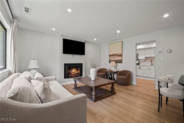 26749 Lake Of The Falls Blvd, Olmsted Falls, OH 44138 - living room featuring light wood-type flooring, healthy amount of natural light, recessed lighting, and a warm lit fireplace