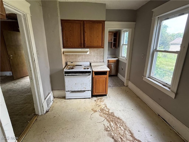 2013 7th St NE, Canton, OH 44704 - kitchen with white gas stove, ventilation hood, brown cabinetry, light countertops, and tasteful backsplash