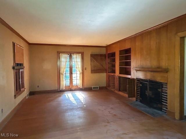 175 Curtis Dr, Avon Lake, OH 44012 - unfurnished living room with ornamental molding, a fireplace with flush hearth, french doors, built in features, and wood walls