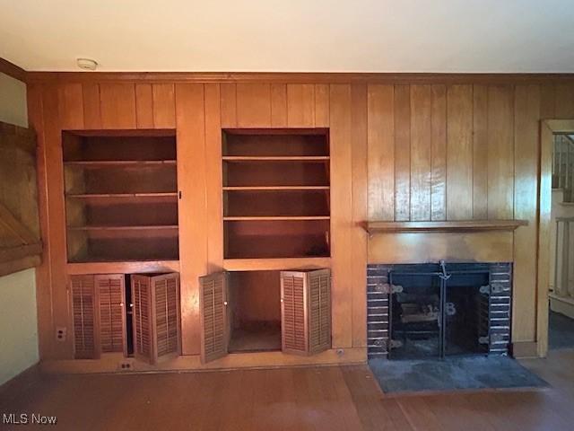 175 Curtis Dr, Avon Lake, OH 44012 - unfurnished living room with a fireplace with flush hearth, wooden walls, and wood finished floors