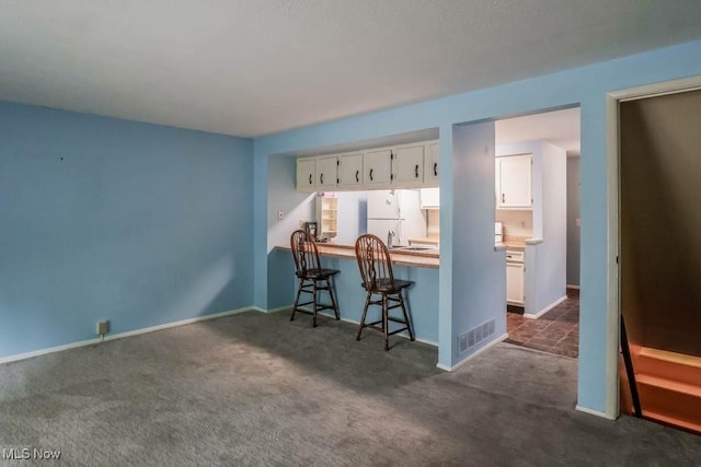 3888 Lake Run Blvd, Stow, OH 44224 - kitchen featuring freestanding refrigerator, white cabinets, dark colored carpet, and a kitchen breakfast bar