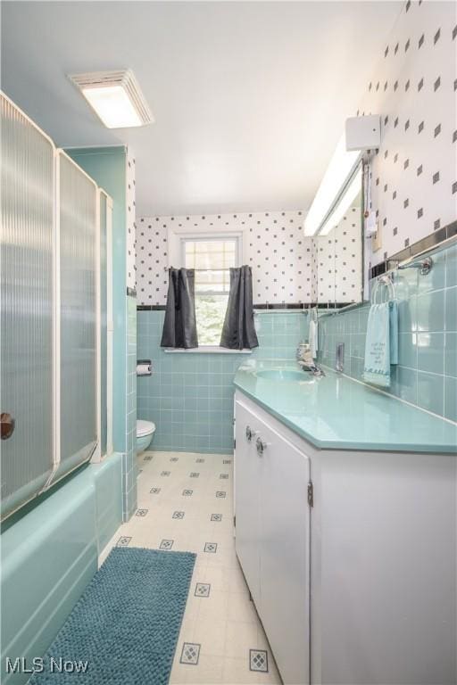 312 S Cleveland Ave, Mogadore, OH 44260 - bathroom with wallpapered walls, tile walls, vanity, bath / shower combo with glass door, and tile patterned floors