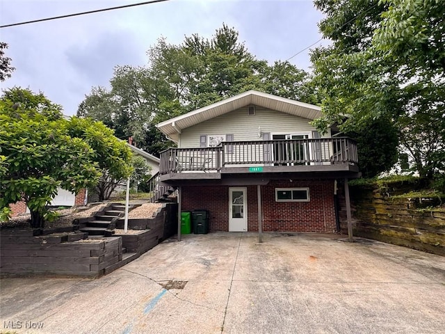 1587 Hilda St, Lakemore, OH 44250 - view of front of home featuring stairway, a deck, a patio area, and brick siding