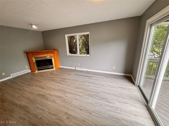 1587 Hilda St, Lakemore, OH 44250 - unfurnished living room featuring wood finished floors, a fireplace with flush hearth, and a textured ceiling