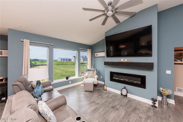 3508 Boos Rd, Huron, OH 44839 - living room featuring wood finished floors, a glass covered fireplace, vaulted ceiling, and a ceiling fan