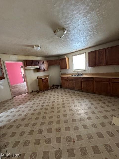 3454 Fulton Rd, Cleveland, OH 44109 - kitchen featuring a textured ceiling, light countertops, and brown cabinets