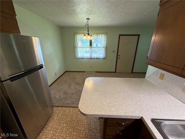122 N Fairview Ave, Dover, OH 44622 - kitchen featuring freestanding refrigerator, a textured ceiling, light countertops, hanging light fixtures, and a peninsula