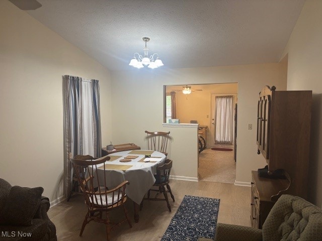 209 Potters Cir, Girard, OH 44420 - dining room with a chandelier, light wood-style floors, vaulted ceiling, and a textured ceiling