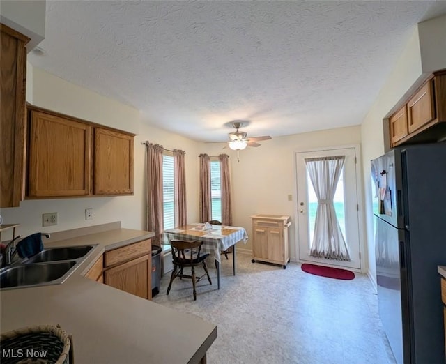 209 Potters Cir, Girard, OH 44420 - kitchen featuring freestanding refrigerator, healthy amount of natural light, brown cabinetry, a ceiling fan, and a textured ceiling