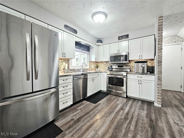133 Argali Pl, Cortland, OH 44410 - kitchen with stainless steel appliances, white cabinetry, dark wood finished floors, decorative backsplash, and a textured ceiling