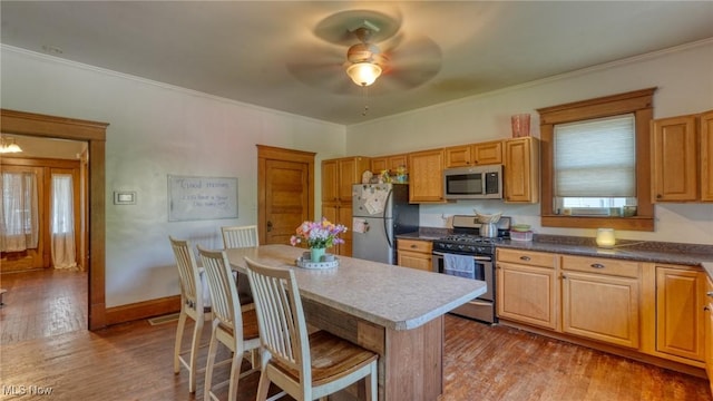 221 N 9th St, Cambridge, OH 43725 - kitchen with stainless steel appliances, a ceiling fan, wood finished floors, a kitchen island, and a kitchen breakfast bar