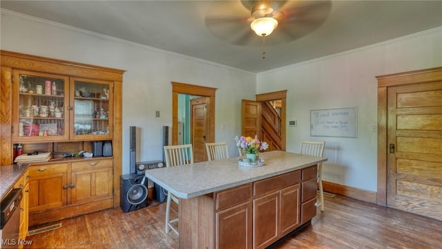 221 N 9th St, Cambridge, OH 43725 - kitchen with dark wood-style flooring, a ceiling fan, a kitchen bar, crown molding, and glass insert cabinets