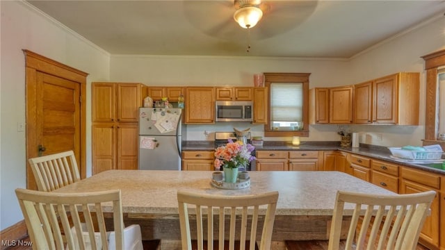 221 N 9th St, Cambridge, OH 43725 - kitchen featuring stainless steel appliances, a kitchen island, a ceiling fan, crown molding, and dark countertops