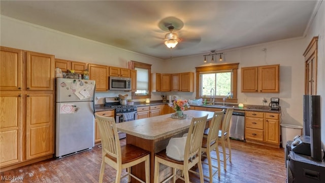 221 N 9th St, Cambridge, OH 43725 - kitchen with stainless steel appliances, a breakfast bar area, ceiling fan, wood finished floors, and ornamental molding