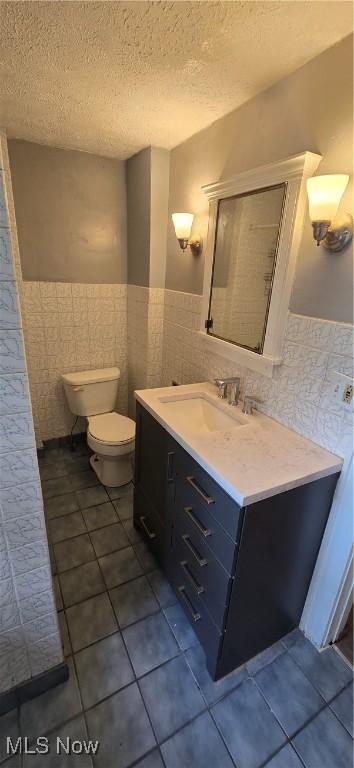 914 Dan St, Akron, OH 44310 - bathroom with tile walls, tile patterned floors, vanity, wainscoting, and a textured ceiling