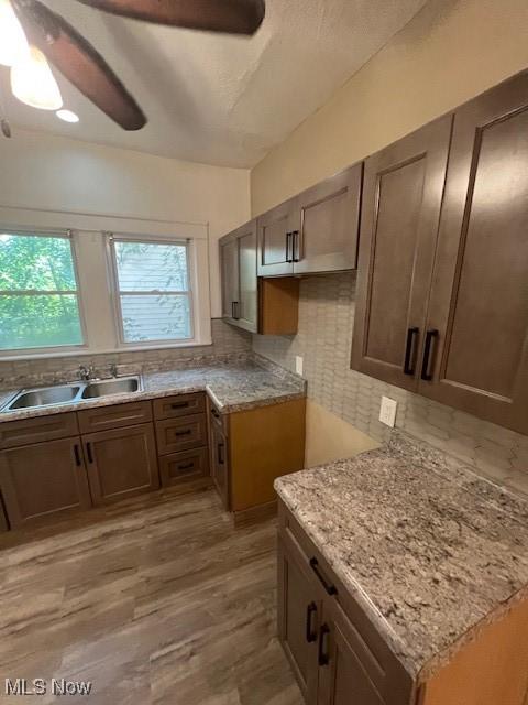 12208 Ingomar Ave, Cleveland, OH 44108 - kitchen with decorative backsplash, a ceiling fan, light stone counters, and light wood-style floors