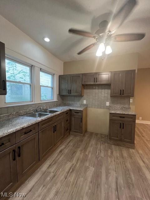12208 Ingomar Ave, Cleveland, OH 44108 - kitchen with light wood finished floors, a ceiling fan, decorative backsplash, and dark brown cabinets