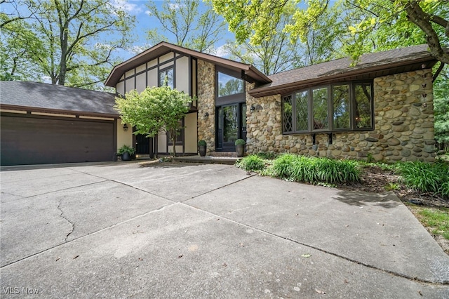5108 Great Oaks Pkwy, Independence, OH 44131 - view of front of house with stone siding, an attached garage, driveway, and roof with shingles
