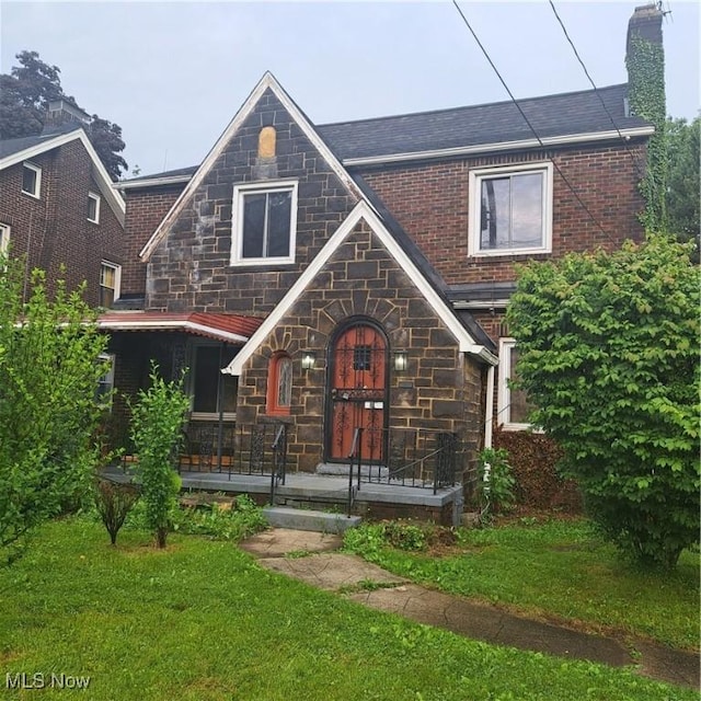 1859 Selma Ave, Youngstown, OH 44504 - view of front of house with stone siding, a chimney, a front lawn, and covered porch