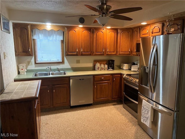 1321 Congo Arroyo Rd, New Cumberland, WV 26047 - kitchen featuring stainless steel appliances, brown cabinetry, ceiling fan, tile countertops, and a textured ceiling