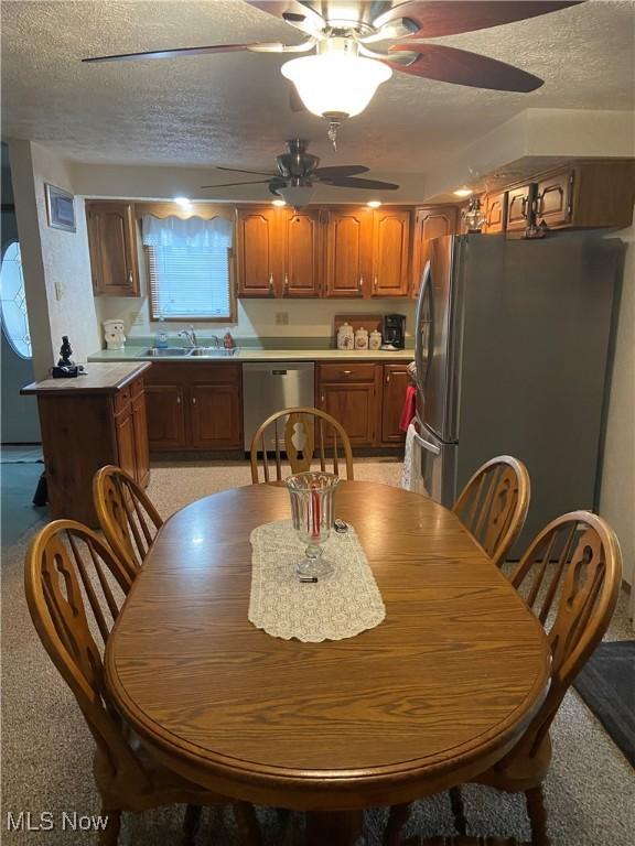 1321 Congo Arroyo Rd, New Cumberland, WV 26047 - kitchen with stainless steel appliances, a textured ceiling, ceiling fan, brown cabinetry, and light countertops