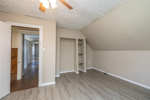 4311 Woburn Ave, Cleveland, OH 44109 - bonus room featuring wood finished floors, a textured ceiling, built in shelves, ceiling fan, and lofted ceiling